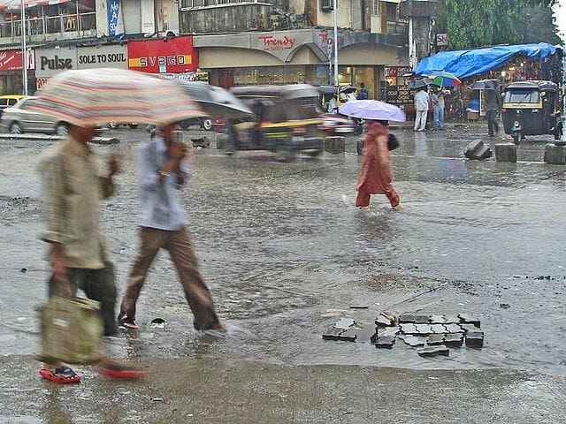 people walking on a waterlogged road in Mumbai