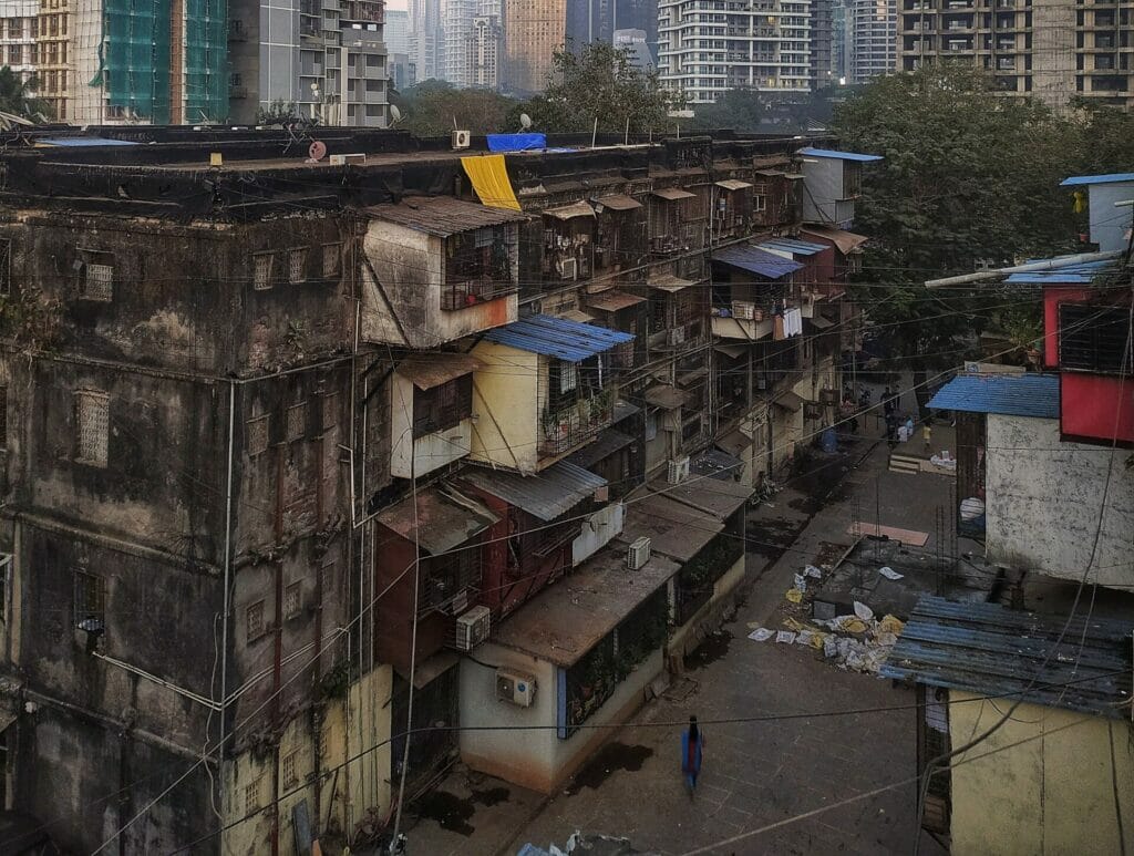 A chawl building in front of a few tall buildings