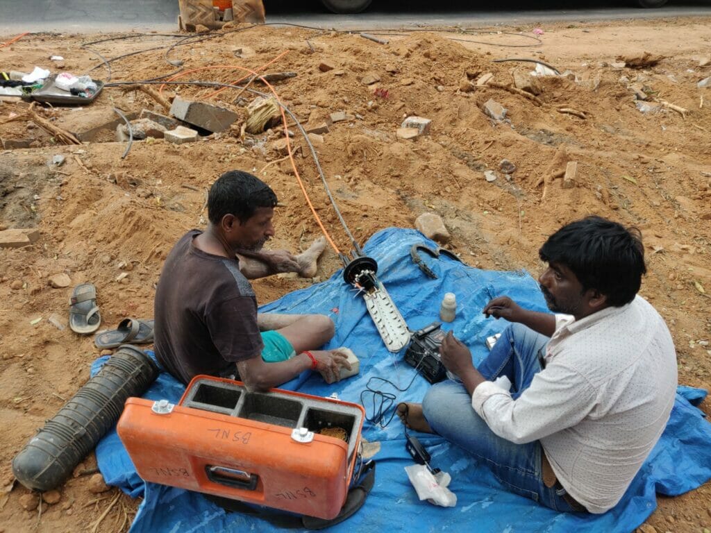 Men rewiring an underground/overhead communication wire connected to a communications repeater on Bellary road. 