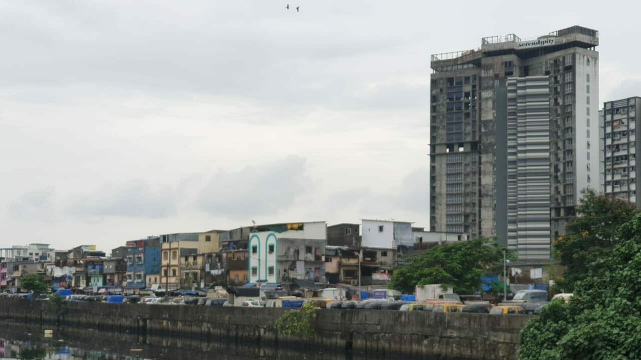 A high rise building next to Mumbai slums.