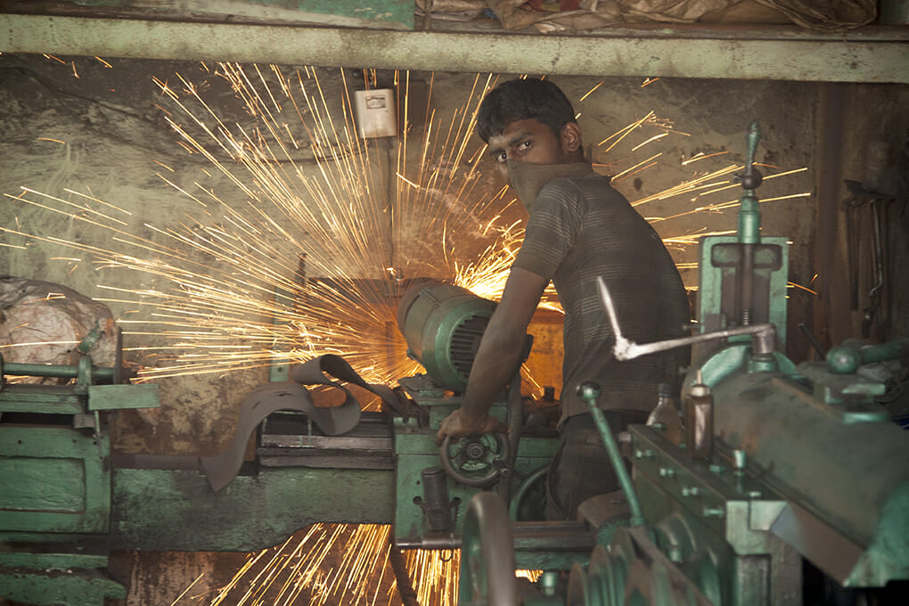 A worker in Dharavi using equipment with sparks emitting 