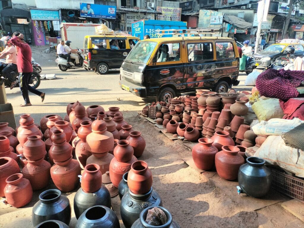 Clay pots drying on the ground before a street with vehicles