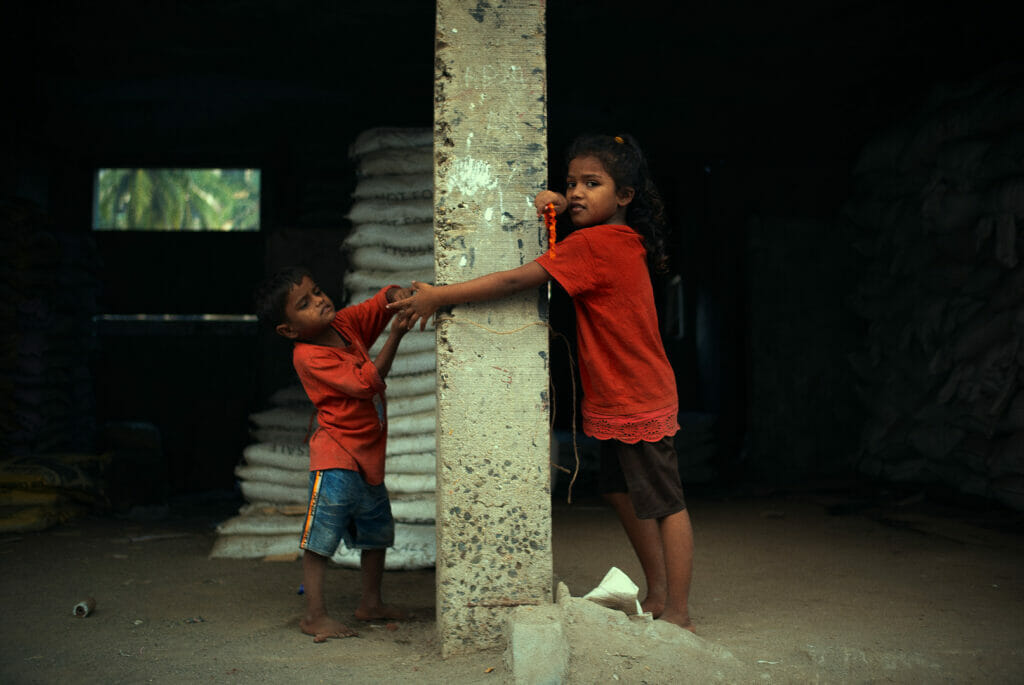 Two kids playing next to a pillar at a construction site in Versova