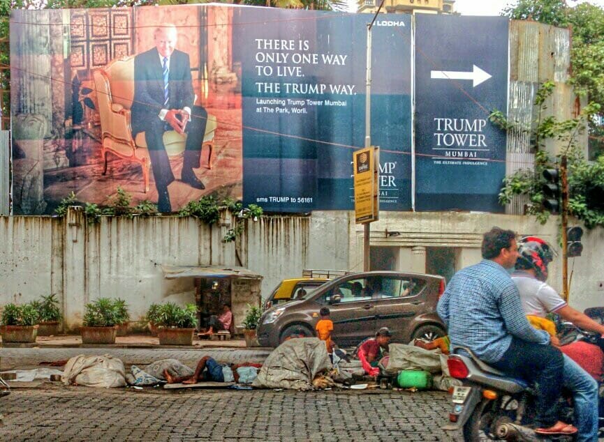 People asleep on the road in front of a Trump tower hoarding 