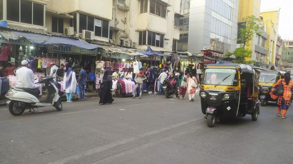 People walk on the road instead of footpath, which has stalls of clothes, on linking road in Bandra 