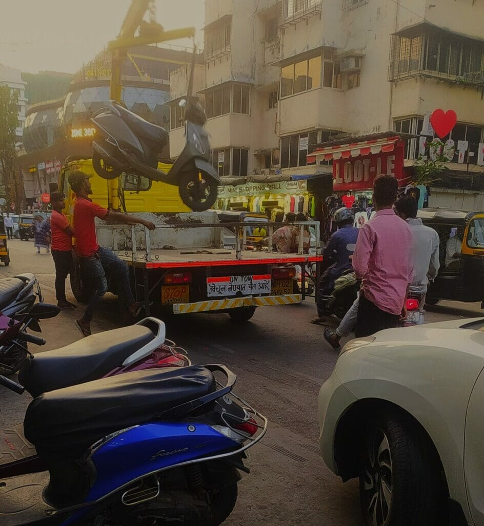 A tow vehicle taking a scooter parked in a no parking area near the Linking Road market in Bandra 