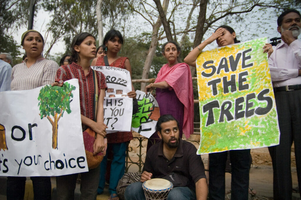 People at protest with 'save the trees' posters.