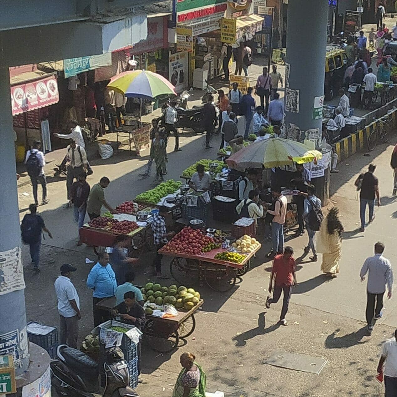 Fruit vendors and other hawkers under a sky walk near station road 