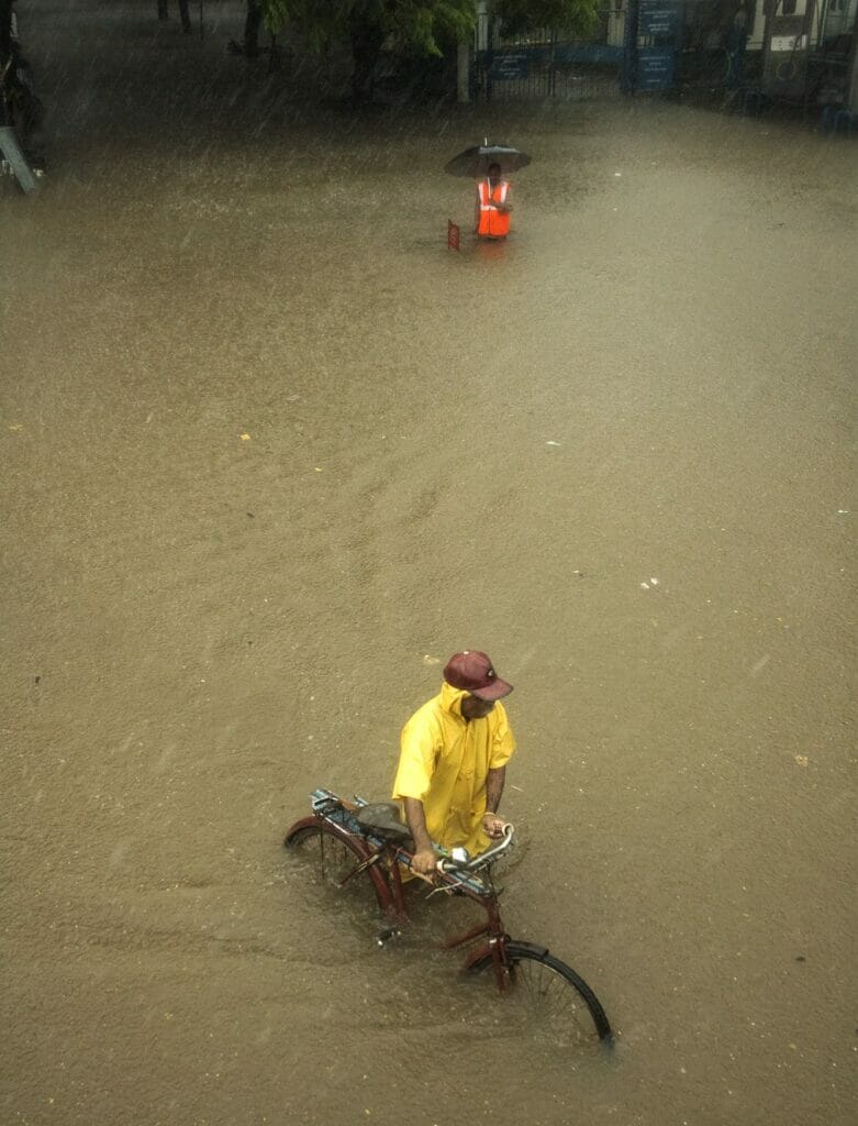 man pushing his cycle through flooded waters 