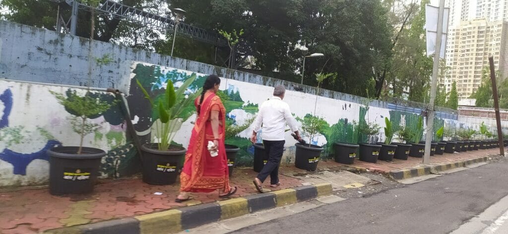 people walking on footpath where space is taken by newly installed planters 