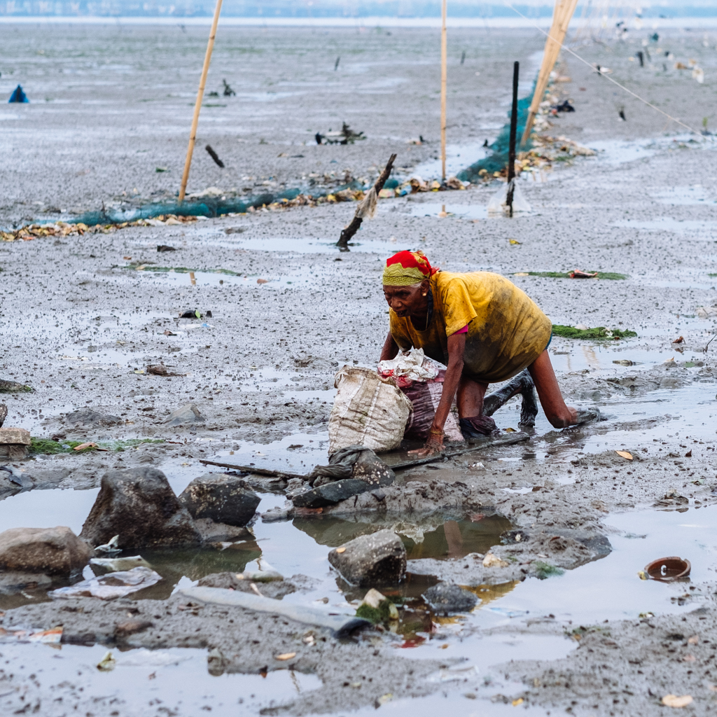 Woman practices the traditional work of collecting shellfish caught from Thane Creek.