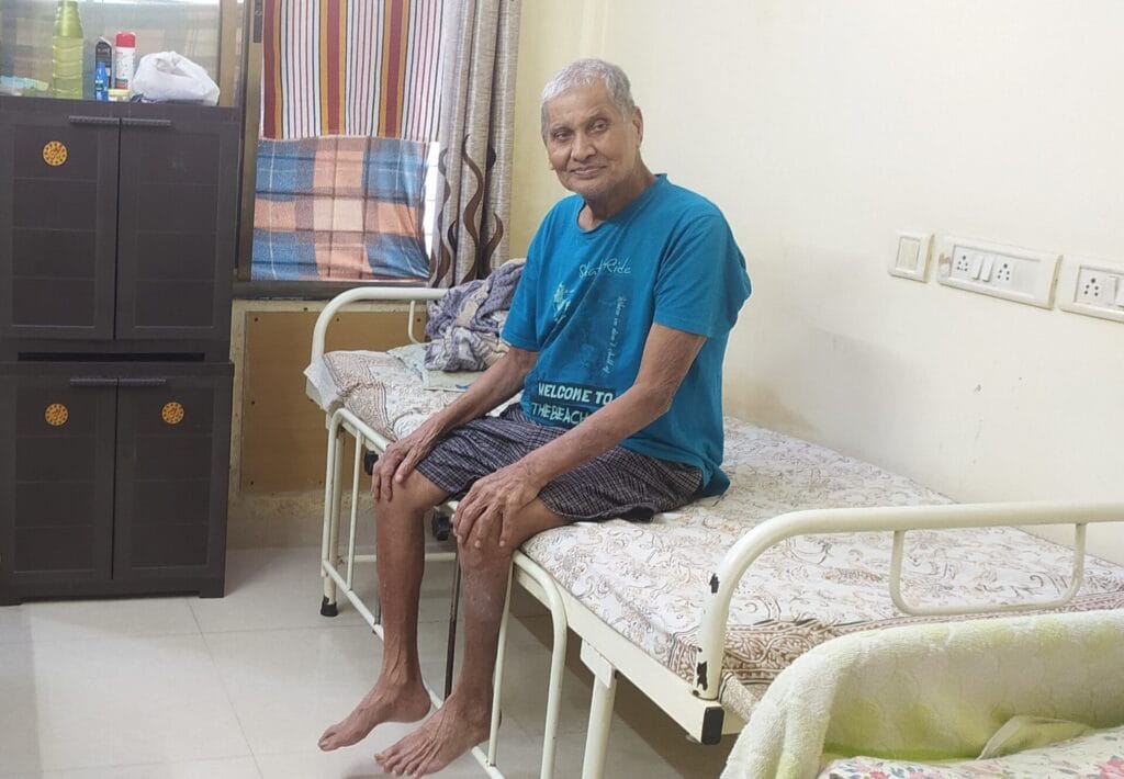 Senior citizen sitting on his bed at an old age home 
