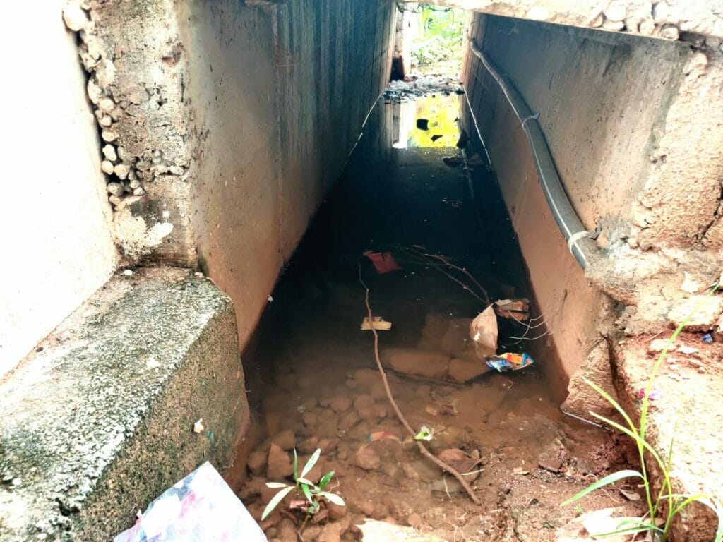 A drain with stagnant water and garbage