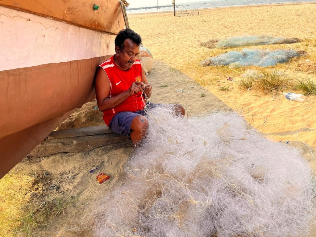 A fisherman mending his nets before he ventures out in the sea. 
