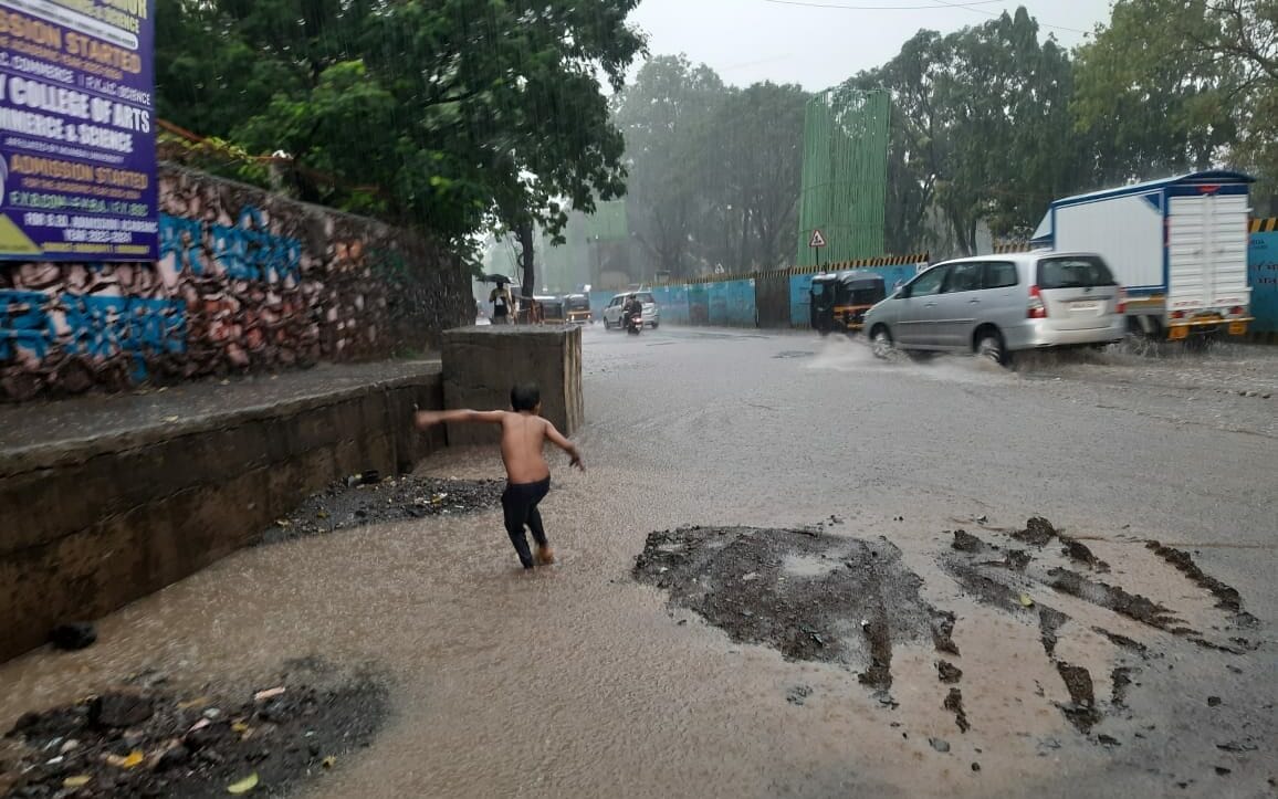 child playing on a flooded road in heavy rains