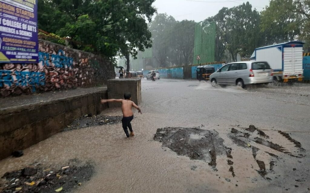 child plays on a water logged road