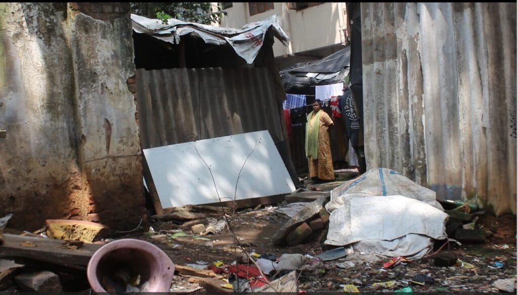 A woman standing outside a manual scavenging settlement