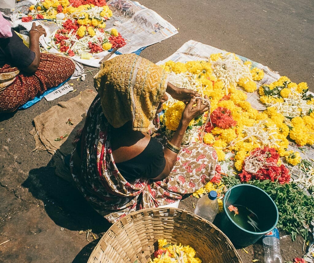 A woman street vendor using a cloth to shield her head from the strong summer sun.