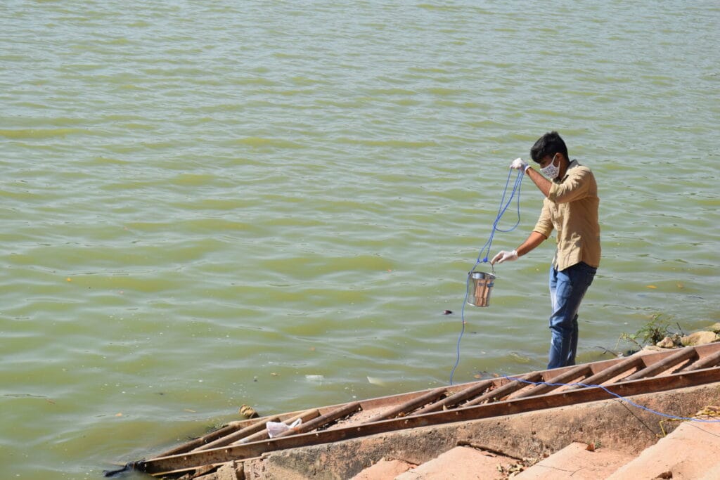 A volunteer collects a water sample from a lake 